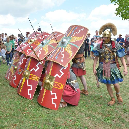 authentisch gekleidete Römer in historischer Formation: Darstellung römischer Legionäre in Formation mit einer Schutzmauer aus Schildern, durch die Speere ragen 
