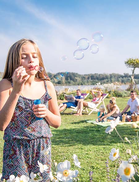 Mädchen auf der Picknick-Wiese an der Donaulände Tulln und lässt Seifenblasen steigen